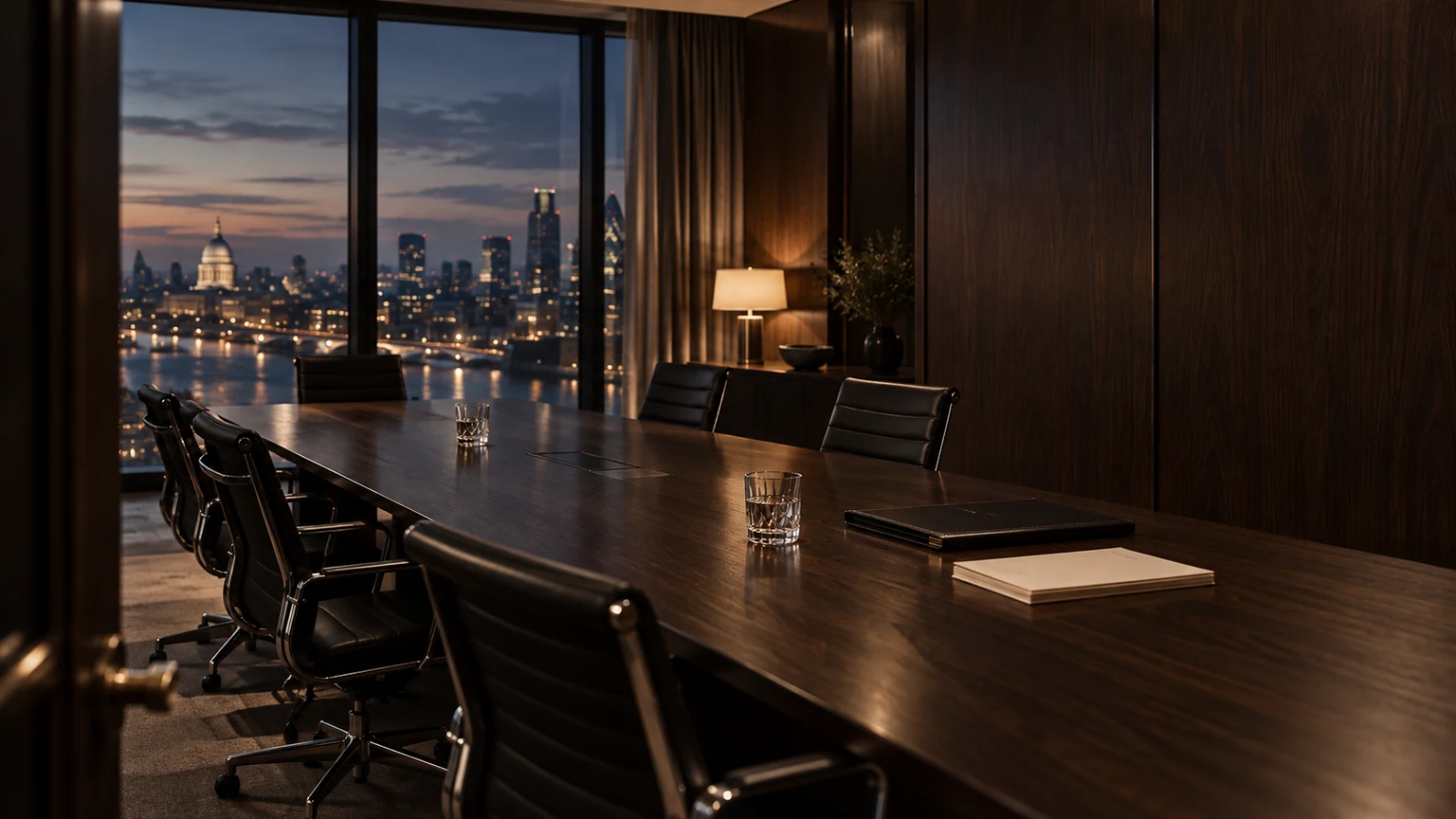 Private London boardroom at dusk with a dark walnut conference table, black leather chairs and warm lamplight.